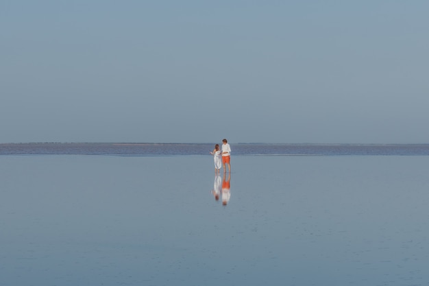 A man and a woman walk on the smooth water of the lake