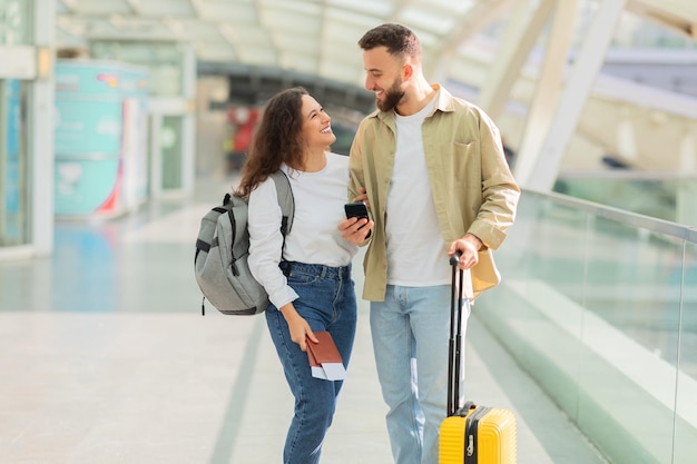 man and woman walking through airport with luggage