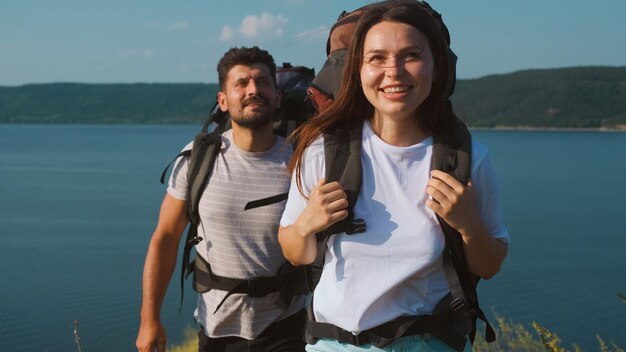 The man and woman walking with backpacks along the beautiful coast