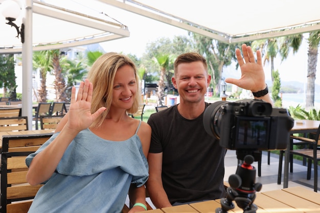 Man and woman waving at camera young family bloggers concept