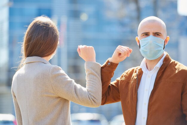 Photo man and woman wearing mask bumping elbow