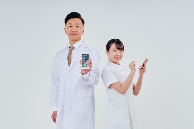 Man and woman wearing white coats operating smartphones