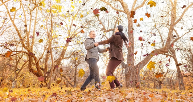 Un uomo e una donna che girano insieme tenendosi per mano e si godono il soleggiato clima autunnale nel parco due amori...