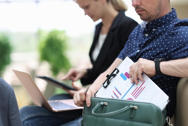 Man and woman with documents charts and laptop working at airport closeup