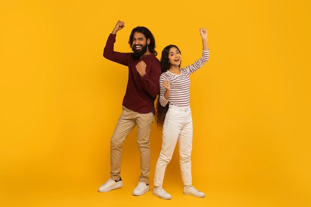 Photo man and woman with fists pumped on yellow background