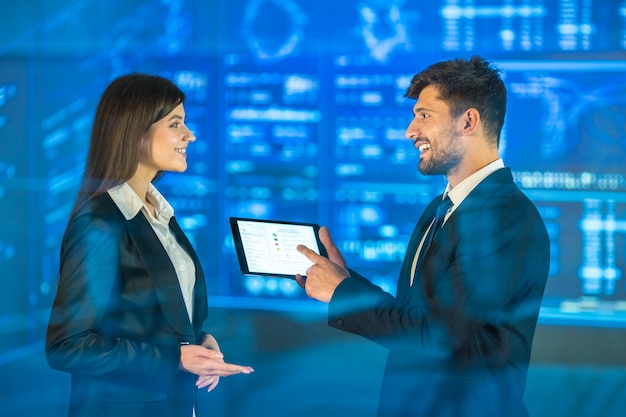 The man and woman with a tablet talk on the virtual screen background