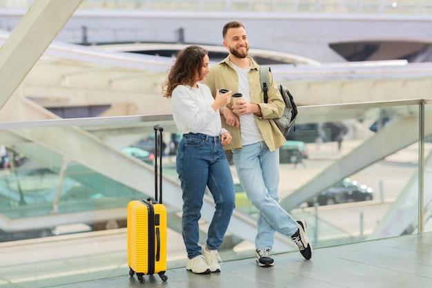 Man and woman with takeaway coffee waiting flight at airport