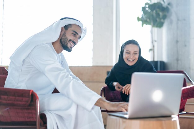 Man and woman with traditional emirates clothes working in a business office of Dubai