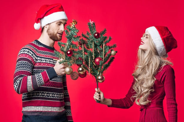 Man and woman with trees in their hands holiday toys decoration red background