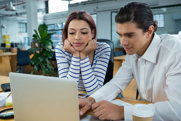 Man and woman working on laptop at desk