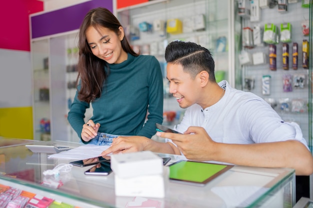 Un uomo e una donna che lavorano insieme controllando i registri degli accessori del telefono cellulare