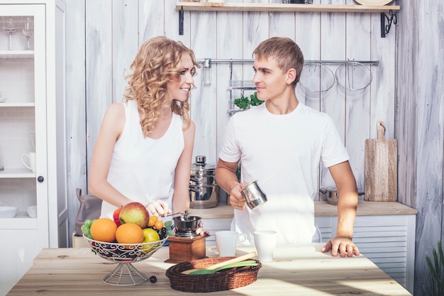 Photo man and woman young and beautiful couple in the kitchen home cook and have breakfast together