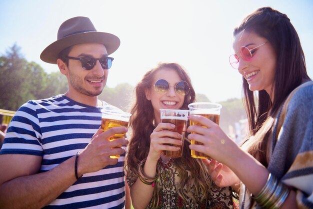 Photo man and women holding drink in glasses against sky