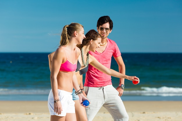 Man and women playing boule on beach