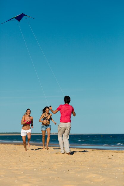 Man and women running on beach with kite