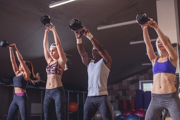 Man and women with coach at kettlebell functional training in fitness center