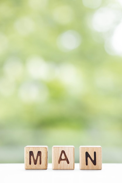 Man word is written on wooden cubes on a green summer background Closeup of wooden elements