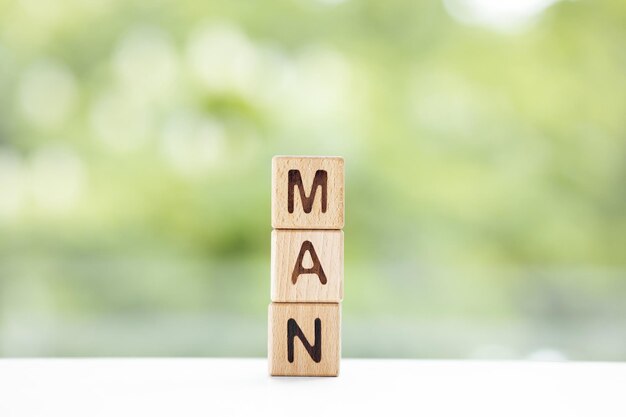 Man word is written on wooden cubes on a green summer background Closeup of wooden elements