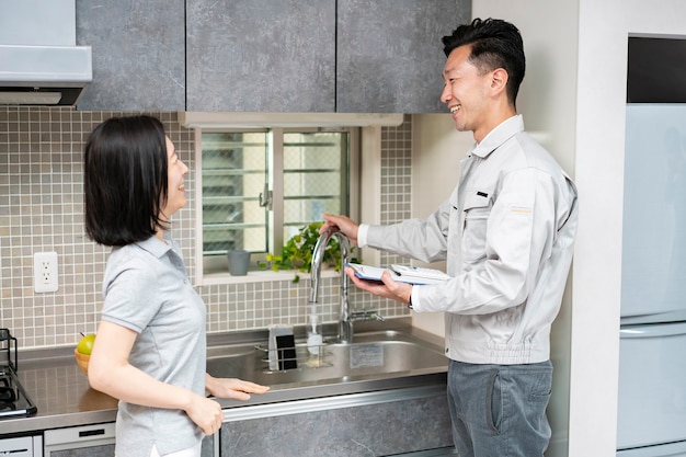 A man in work clothes explaining to a woman at kitchen