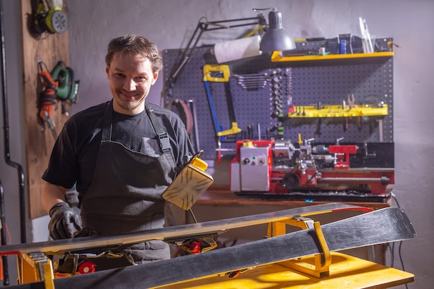 A man in work clothes repairman in the workshop ski service repairing the ski