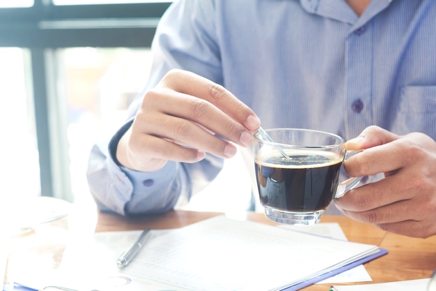 朝のコーヒーを持つオフィスで仕事中の男