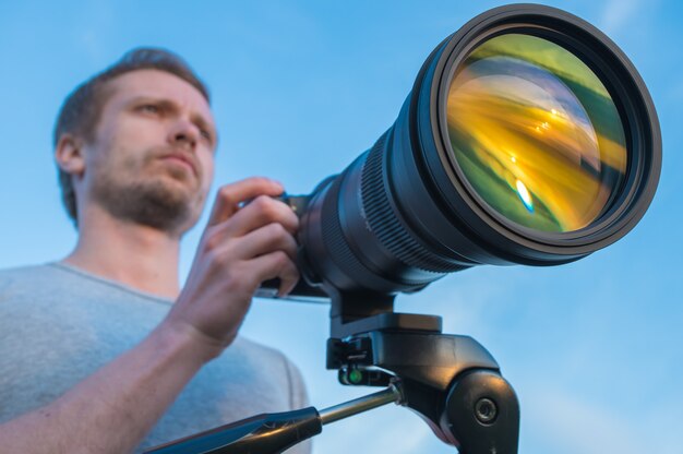 The man work with the camera against the blue sky background