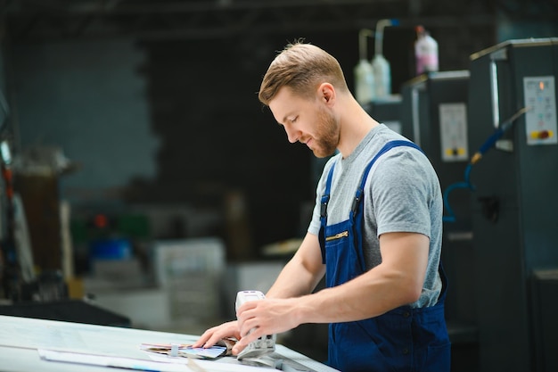 Man worker measuring printing color with spectrometer on the operating desk of the printing plant