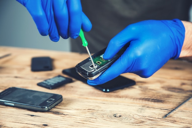 Lavoratore dell'uomo per riparare smart phone sul tavolo di legno