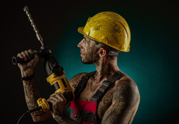 Un uomo con i vestiti da operaio e un casco sporco di fuliggine con un corpo nudo fa una smorfia al minatore della telecamera