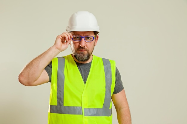 A man worker in a vest and a white construction helmet hat shows hand gestures in different poses on