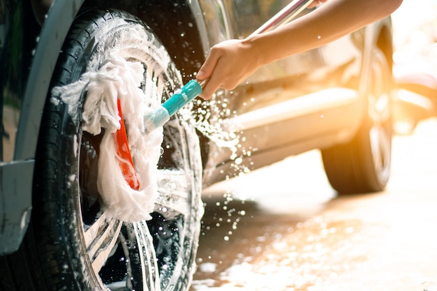 Man worker washing car's alloy wheels in car care.