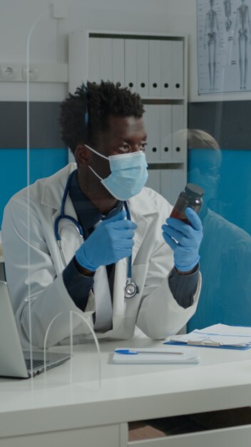 Man working as doctor holding bottle of pills