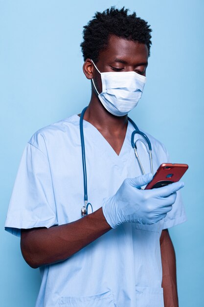 Man working as nurse looking at smartphone in hand