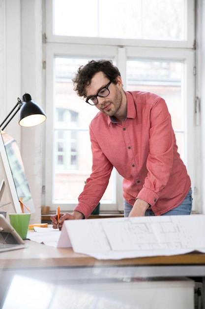 Man working on blueprint at desk in office