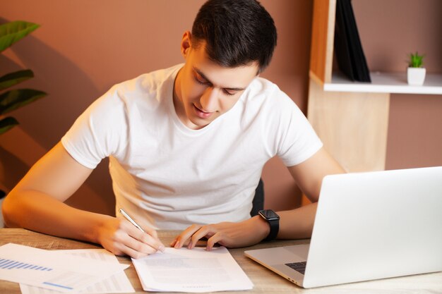 Man working at the computer in the office and filling documents