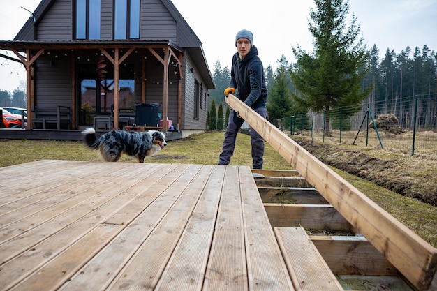 Man working on a deck or terrace with his loyal dog companion in the yard of a countryside home