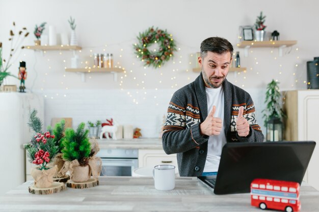 Man working from home communicates with colleagues and friends via video link, using a laptop, for the New Year and Christmas holidays