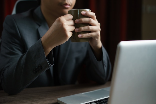 Man working from home using computer and drinking cup of tea