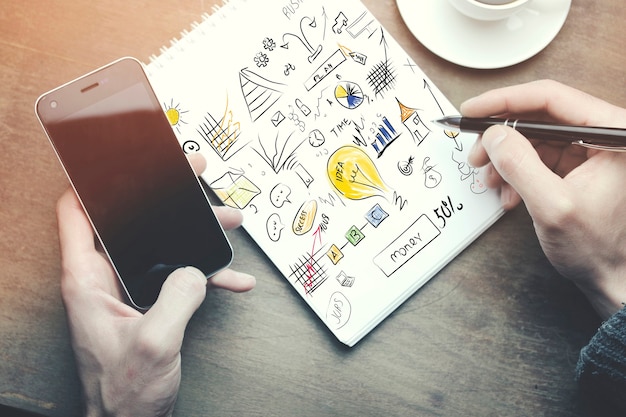 Man working -hand pen and phone, cup of coffee on wooden table