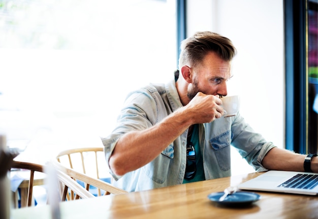 コーヒーショップでノートパソコンで働く男