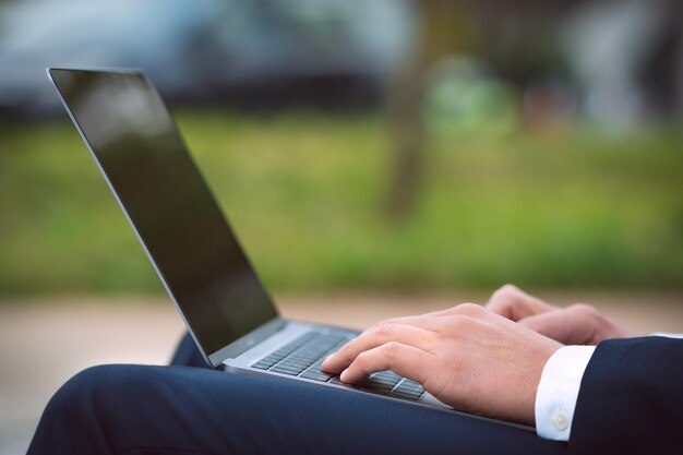 Man working on his laptop outdoors Business man hands typing on computer