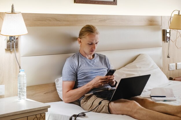 Man working in hotel room on the bed with laptop vacation