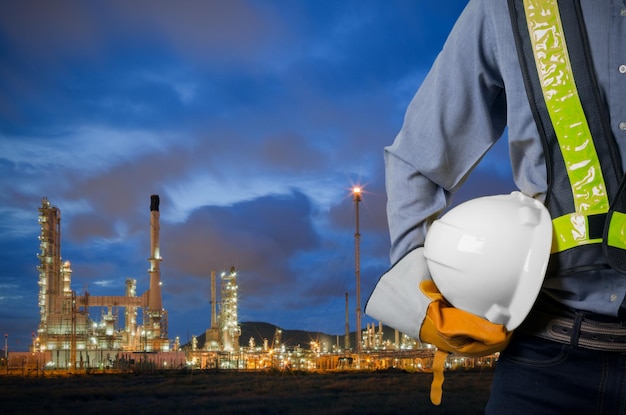 Photo man working at illuminated commercial dock against sky oil refinery