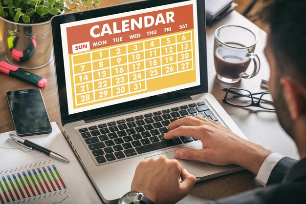 Man working on a laptop calendar on the screen