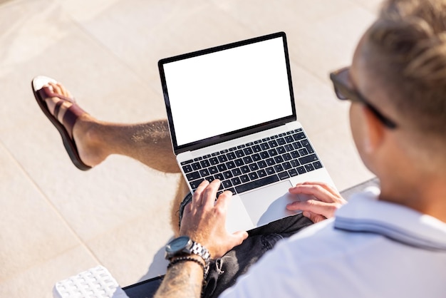 Man working on laptop computer outdoors over the shoulder view