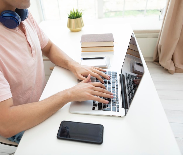 Man working on laptop at desk with mobile phone and headphones