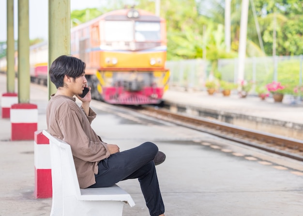 タイの鉄道駅の近くで携帯電話に取り組んでいる男性