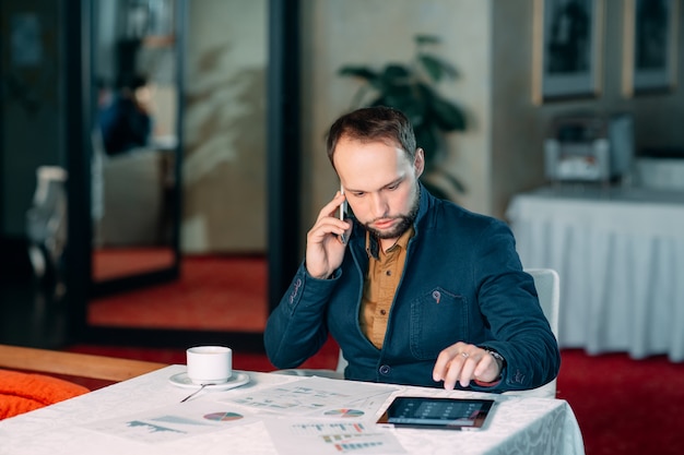 Uomo che lavora in ufficio e analizzando alcuni rapporti di calcolo statistico.