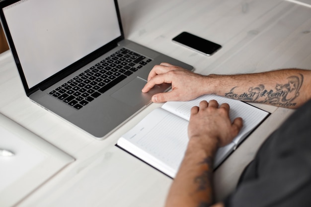 Man working in office with laptop and notebook