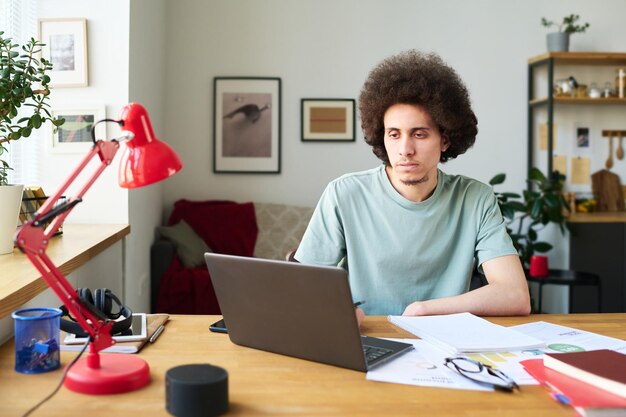 写真 自宅のラップトップでオンラインで作業する男性